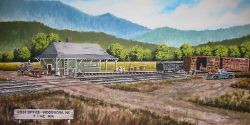 WOODROW DEPOT/POST OFFICE



- Artist DominicNick De Paolo had only a historic photo of one end of the Woodrow Train Station from which to create an artistic rendering of the 1914-1927 structure that served as a depot for the T & NC Railroad in Bethel.  Named for the President at the time, Woodrow Wilson, the structure simultaneously served as a post office, a designation that placed Woodrow on maps to this day. Passengers traveled from Canton to Sunburst and Spruce and all places in between on a small jitney bus that utilized rail tracks.  Rail cars transported pulp wood and sawn lumber from Sunburst logging operation to the Canton paper mill.  The nearby kaolin mine used a tram operation to transport clay to railcars for shipment to Canton and beyond while returning to the mine with coal used to fuel steam-generating boilers.  Local apple farmers took advantage of the Woodrow railcars in the fall to transport produce.  Today, Highway #215 shadows the space once occupied by the T & NC railroad tracks.